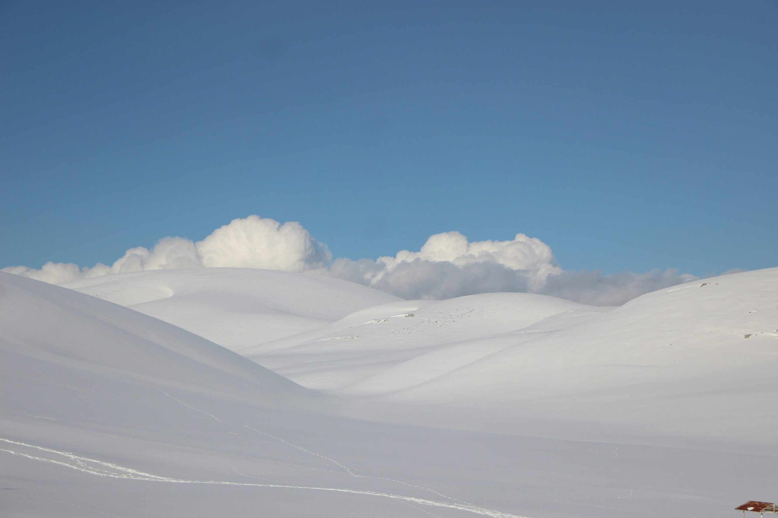 a person on skis in the snow with clouds in the background